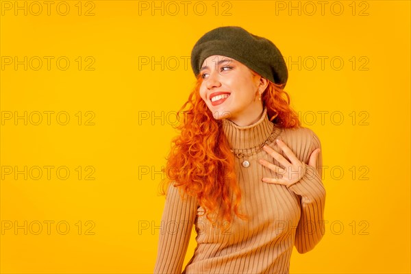 Red-haired woman in beret in studio on a yellow background