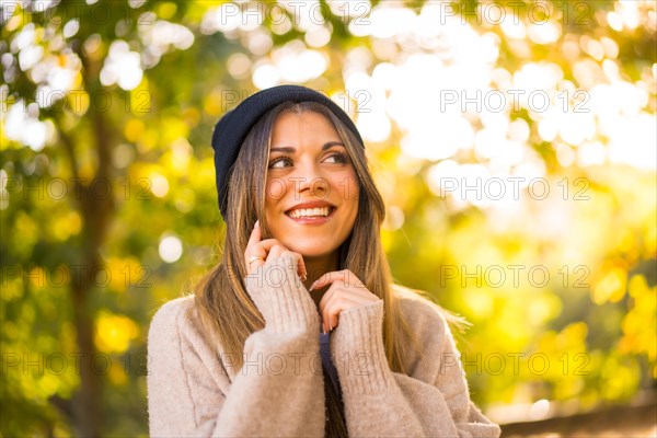 Young blonde girl with a wool cap in autumn at sunset in a natural park