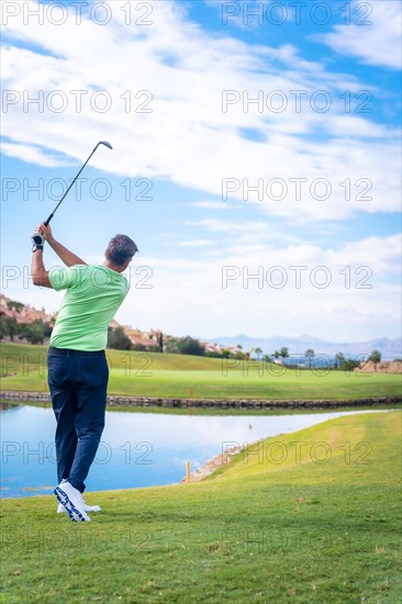 Man playing golf at golf club by a lake