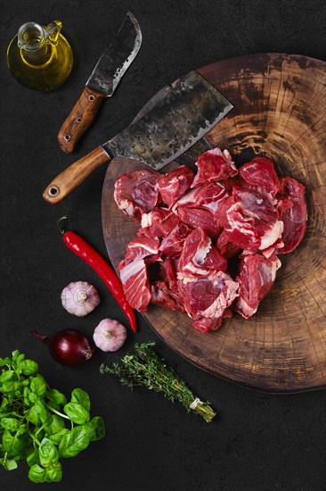 Overhead view of chopping fresh beef meat for goulash or stew on wooden chopping stump