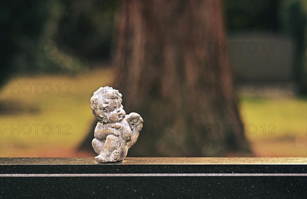 Small angel figure sitting on a gravestone