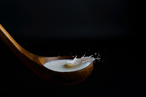 Milk splashing on a wooden ladle