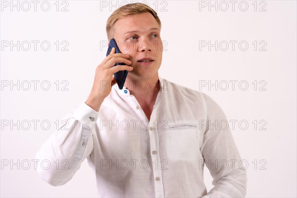 Caucasian blond businessman man making a work call with the phone on a white background