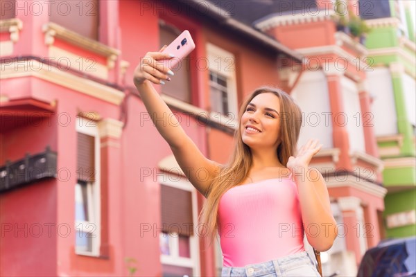 Young blonde caucasian woman in a street with houses with colorful facades behind