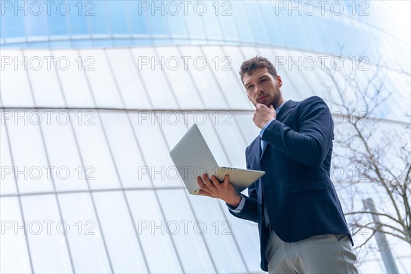 Young businessman looking with a computer in a glass building