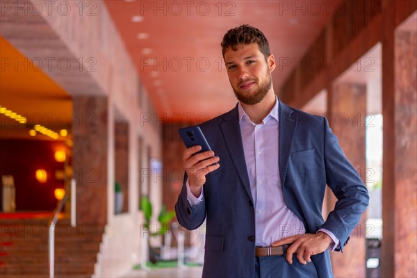 Business or finance corporate man at the entrance of the office with a phone in his hand