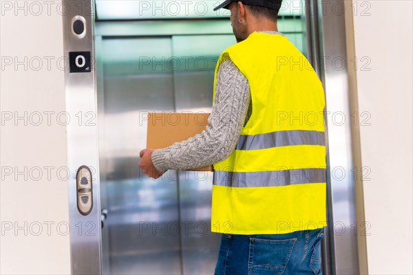 Young delivery man in protective uniform at online order delivery