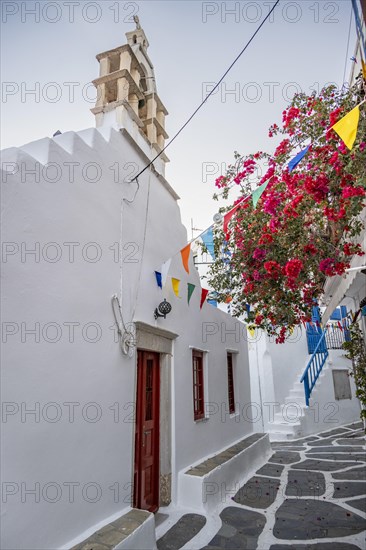White Greek Orthodox Church decorated with flags and bougainvillea