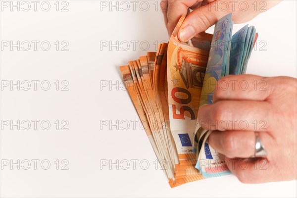 Woman counting euro banknotes on a white table with copy space