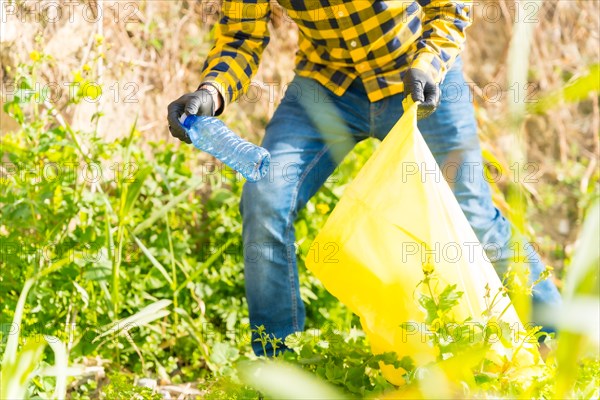 Unrecognizable man's hand collecting plastics in a forest. Ecology concept