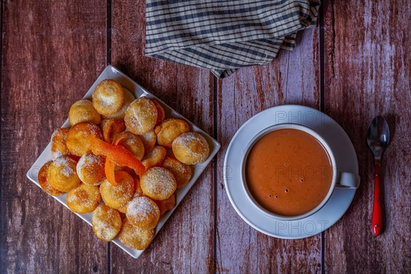 Homemade doughnuts with sugar and hot chocolate in a white mug on a wooden table