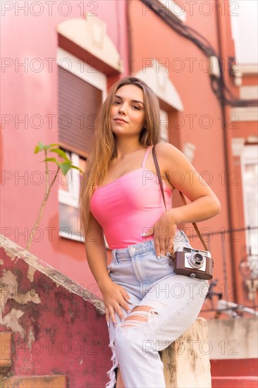 Portrait of young blond caucasian tourist in a street with houses with colorful pink facades