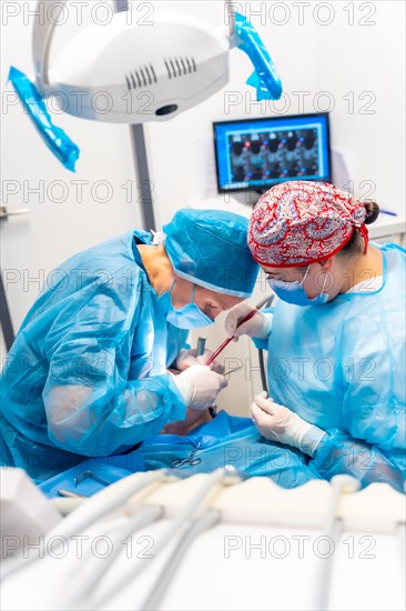 Doctors in blue gowns performing a complicated operation on a patient