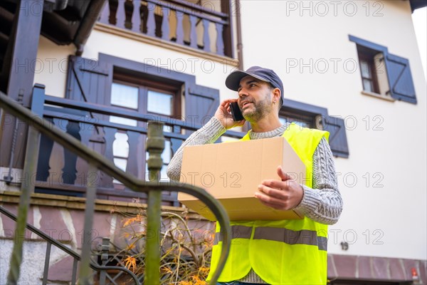 A young delivery man with the box in a protective uniform