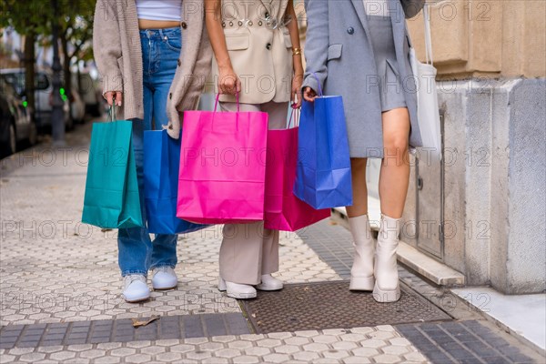 Girlfriends shopping in the offers of the city stores with paper bags