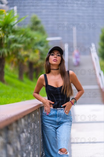 Portrait of a young brunette woman in a black cap and jeans in the city