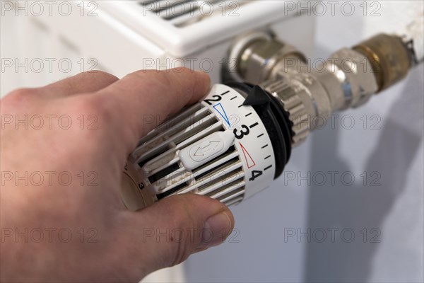 Man's hand turns thermostat