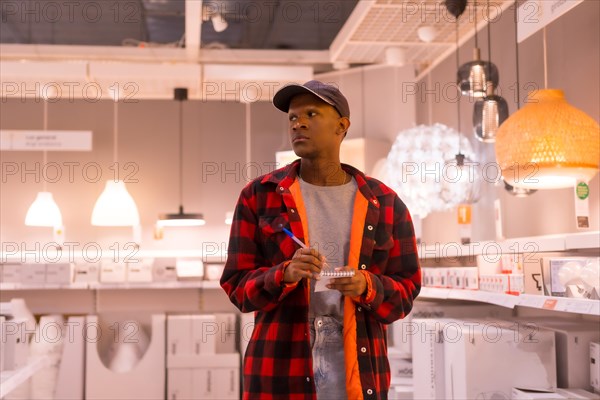 Black ethnic man shopping in a supermarket for lamps