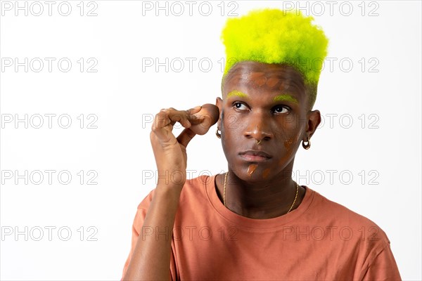 An androgynous black man posing putting on makeup