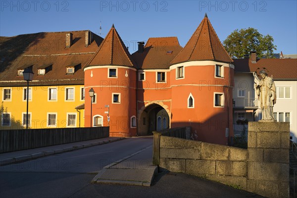 The historic orange building Biertor with the bridge and a statue in the evening light under a clear blue sky