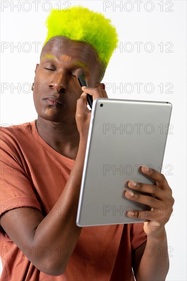 A gay black man putting on makeup