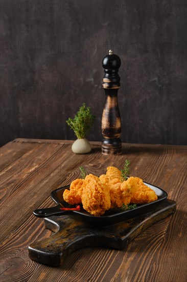 Spicy deep fried breaded chicken wings on shabby serving board