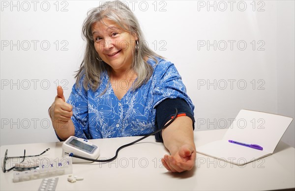 Woman taking her blood pressure with a nod of approval everything ok