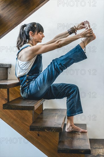 A woman doing stretching exercises on the stairs of her home. Wellbeing concept