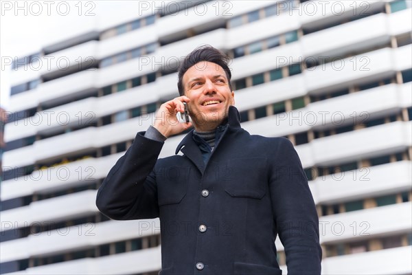 Middle-aged Caucasian businessman talking on the phone in the city smiling
