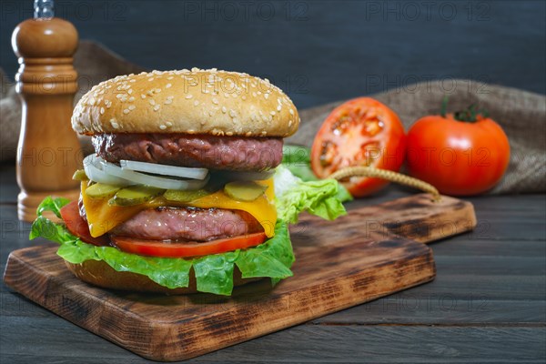 Close-up of a delicious whole hamburger on a wooden board and sauces