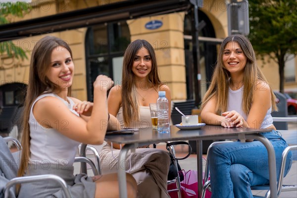 Portrait of young female friends having a drink one afternoon on a cafeteria terrace