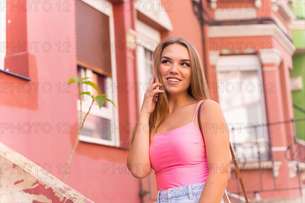Young blonde caucasian tourist in a street with houses with colorful facades