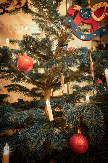 Red Christmas tree balls on a Christmas tree and a rocking horse made of felt with Christmas tree lights