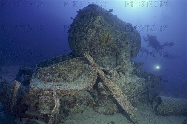 Remains of a steam locomotive from the Second World War on the seabed. Divers in the background. Dive site Thistlegorm wreck