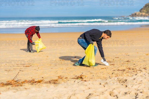 Volunteers collecting plastic from the sand on the beach. Ecology concept