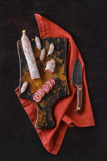 Top view of fermented salami sausages with white mold on wooden cutting board