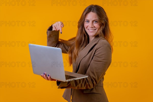 Business woman pointing at a computer on a yellow background