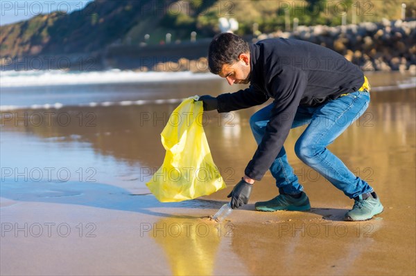 Volunteer man collecting garbage or plastic on the beach. ecology concept