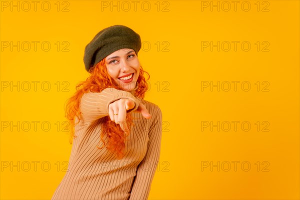 Red-haired woman in beret in studio on a yellow background