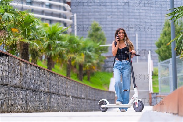 Young woman in the city with an electric scooter talking on the phone