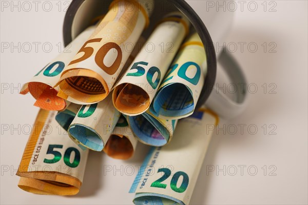 Rolled euro banknotes in a white cup with white background and copy space