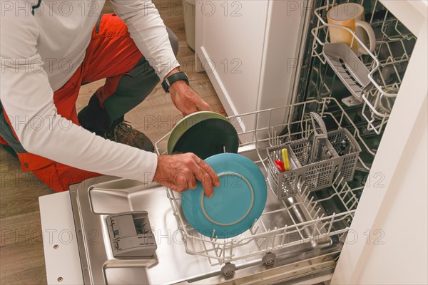 Man in white t-shirt putting the dishes in the dishwasher