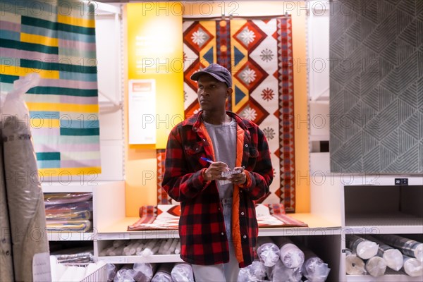 Black ethnic man shopping in a carpet supermarket