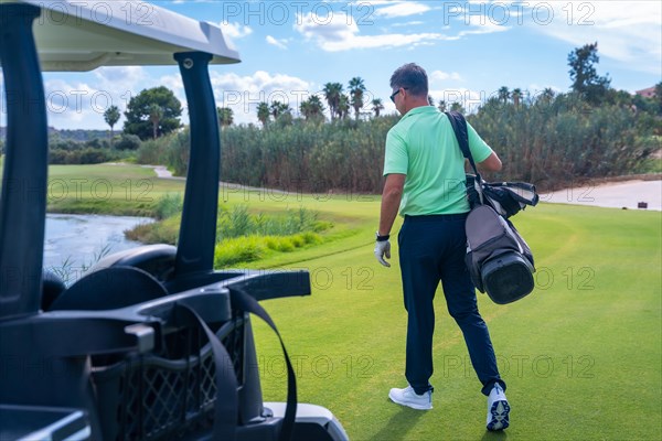 Man in the Buggy with the bag of clubs playing golf