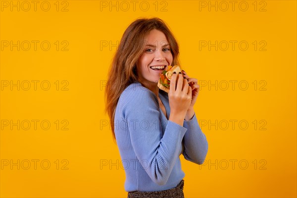 Woman eating a sandwich on a yellow background