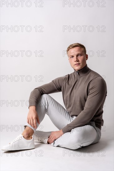 Caucasian blond model with a brown sweater on a white background