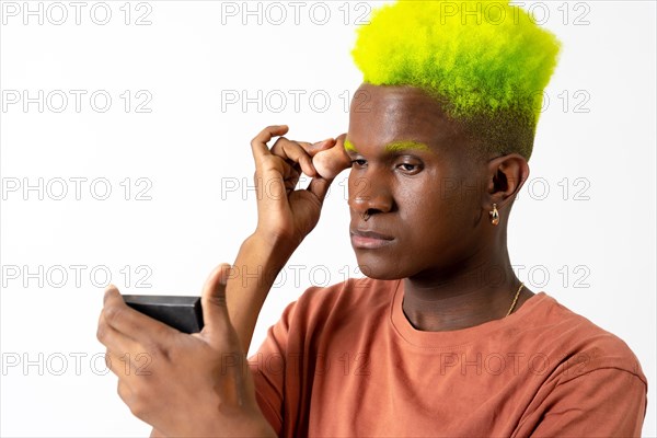 An androgynous black man posing putting on makeup