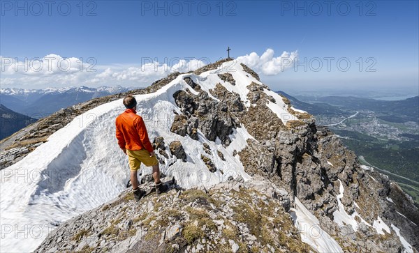 Hiker on the summit ridge of Thaneller with summit cross