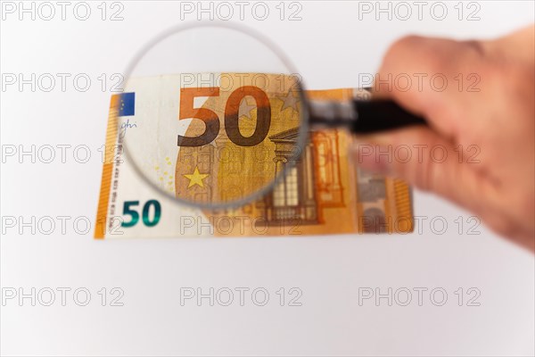 Fifty euro banknote seen with a magnifying glass on a white background and copy space