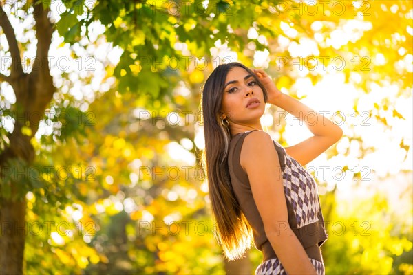 A caucasian brunette woman in autumn at sunset in a natural city park